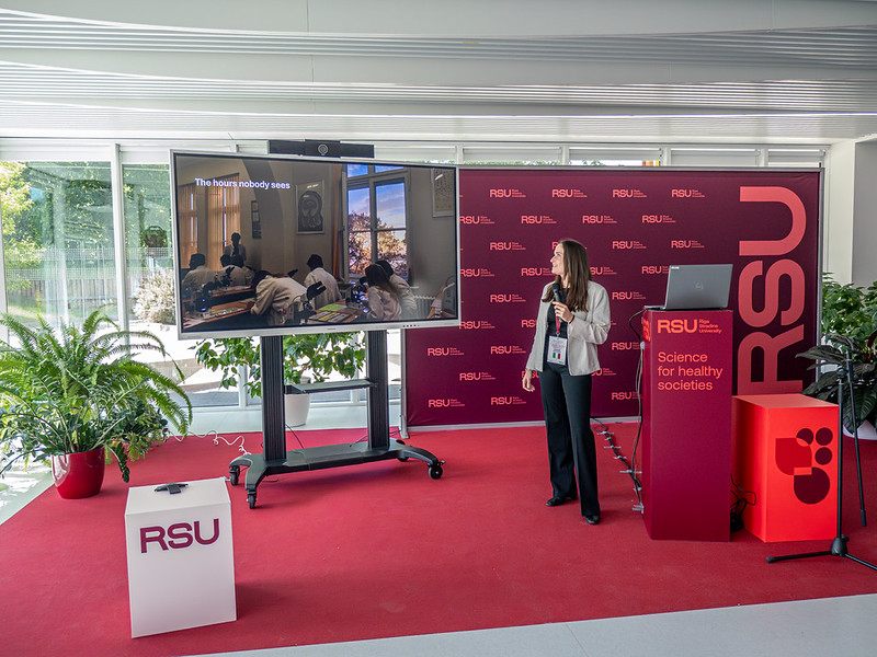 Simona Costa giving a presentation, standing in front of an RSU branded step and repeat