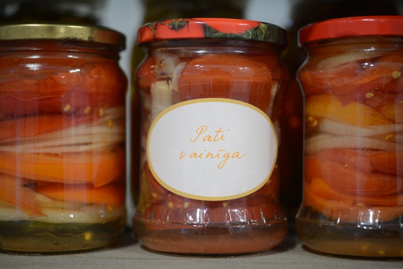 Three jars of preserved vegetables; the centre jar has a label reading ‘Pati vainīga’ (‘It’s your own fault’).