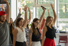 People with left arm raised, participating in an exercise