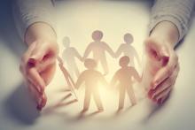 Two open hands facing each other, with a ring of paper cutouts of people in between them