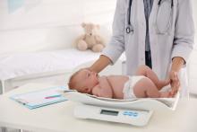 Doctor weighing newborn baby