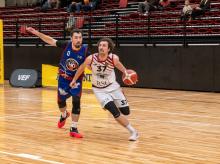 Two basketball players from different teams go after the ball