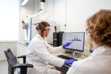 Two researchers in white lab coats sit at computers