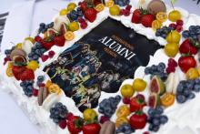 Cake with berries and alumni logo on it