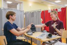 Smiling woman in an RSU tshirt getting her blood pressure measured by a man