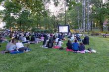 Students sitting in the grass in front of a large screen